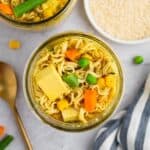 Vegan instant ramen noodles in a glass jar with tofu, carrots and peas.