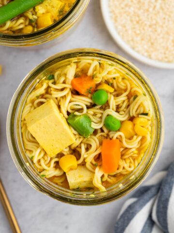 Vegan instant ramen noodles in a glass jar with tofu, carrots and peas.