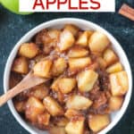 Small wooden spoon scooping up stovetop cinnamon apples from a bowl.
