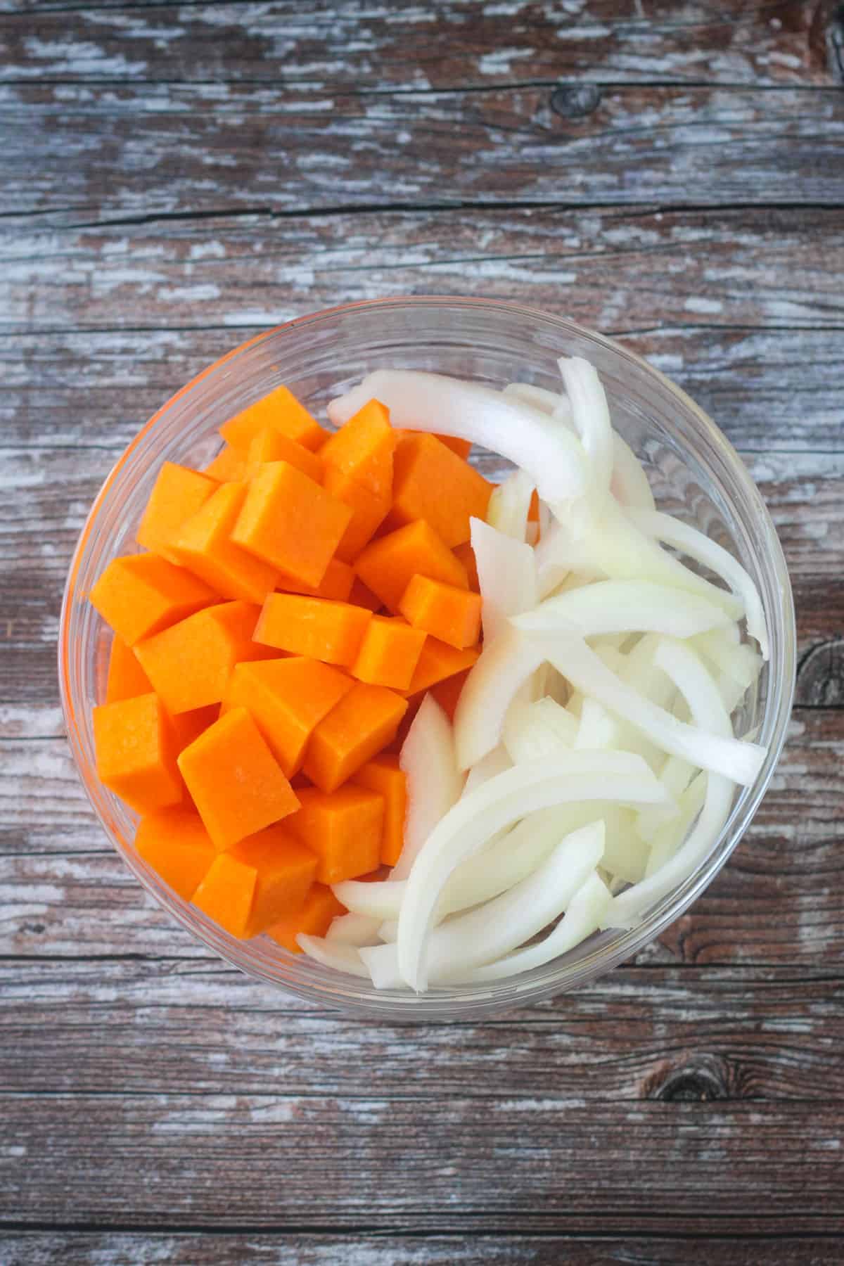 Diced squash and sliced onions in a bowl.
