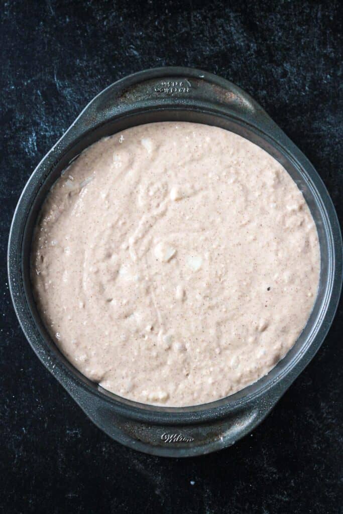 Raw batter in a round cake pan.