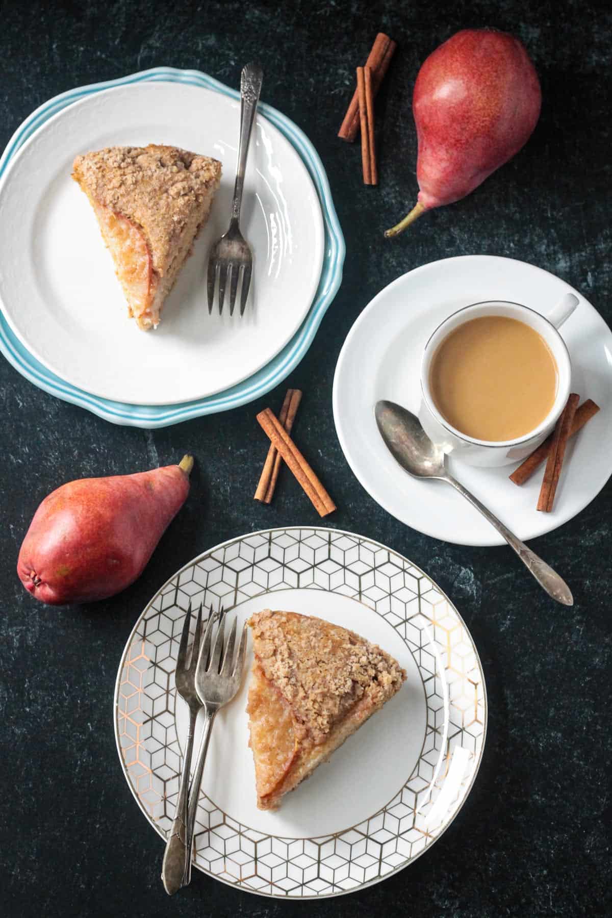 Two plates each with a slice of spiced pear cake next to a cup of coffee.
