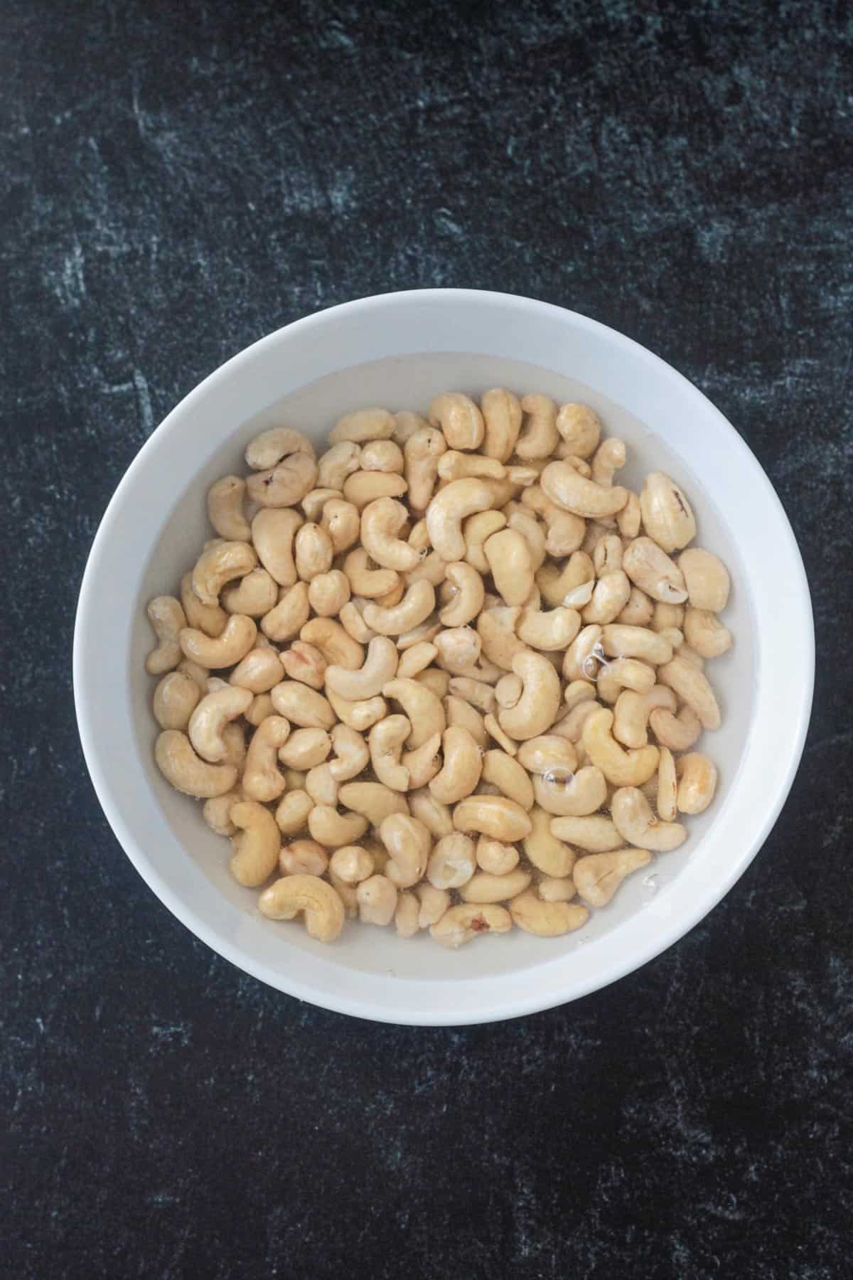 Raw cashews soaking in a bowl of water.