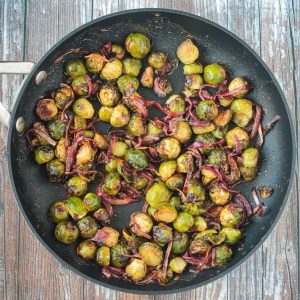 Maple balsamic brussels sprouts and red onion in a large skillet.