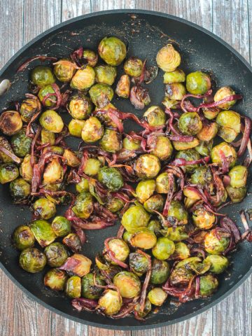 Maple balsamic brussels sprouts and red onion in a large skillet.