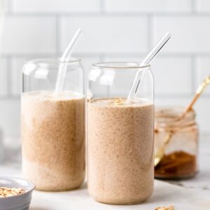 Two oat milk smoothies in glasses with straws.