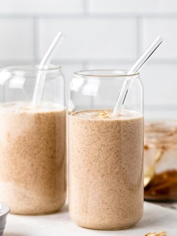 Two oat milk smoothies in glasses with straws.