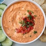 Close up overhead view of cashew dip topped with diced roasted red peppers and chopped fresh parsley.