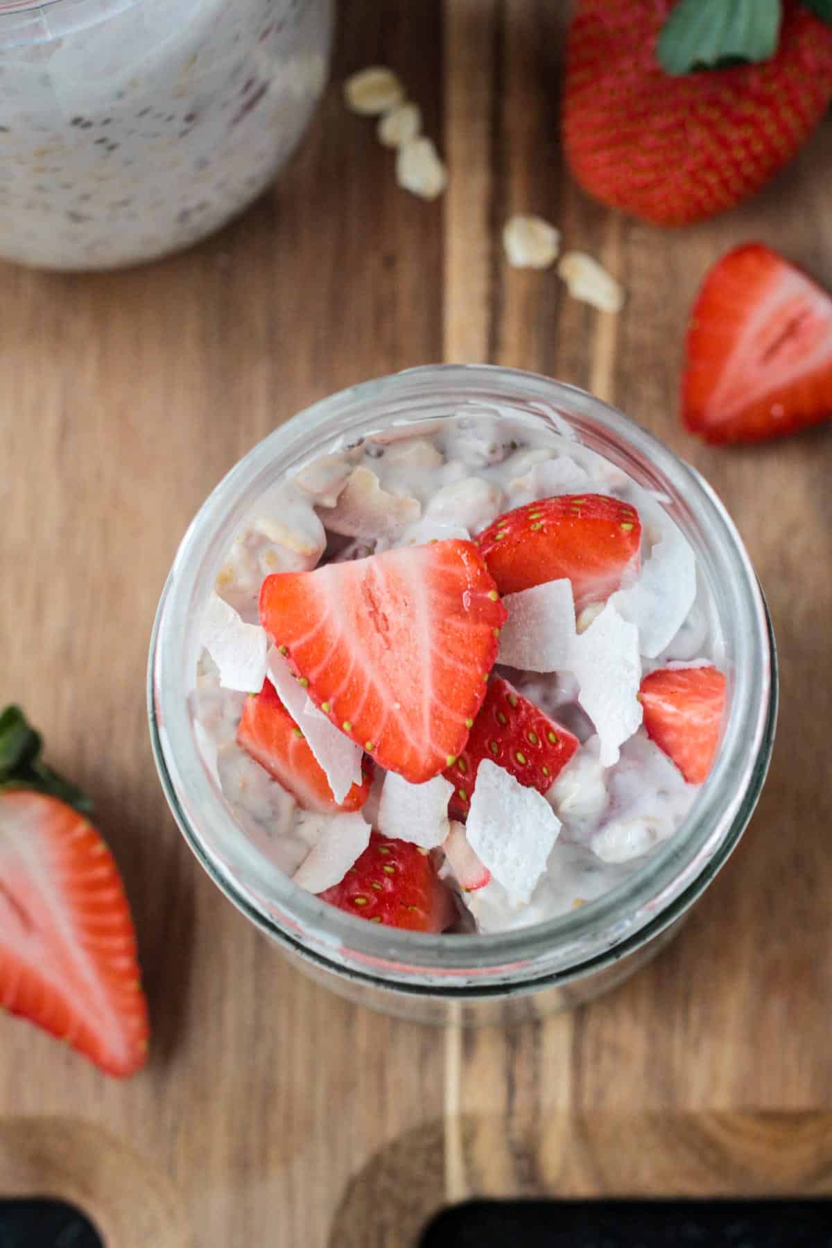 Overhead view of fresh sliced strawberries and coconut flakes on top of overnight oats.