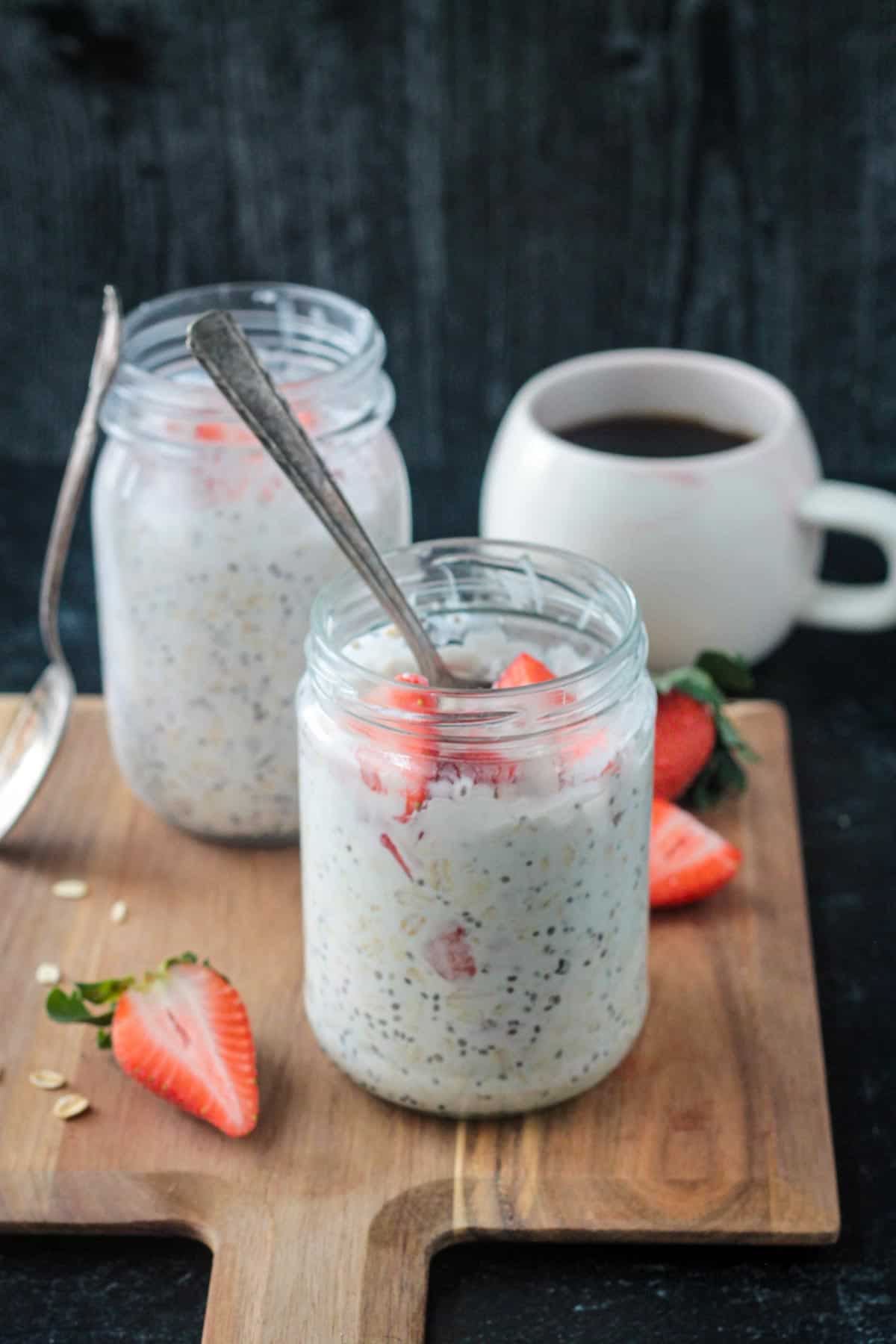 Spoon in a jar of strawberry overnight oats with coconut milk.