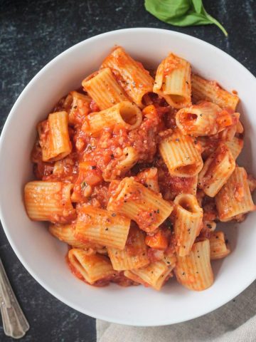 Rigatoni noodles with vegan cauliflower bolognese in a white bowl.