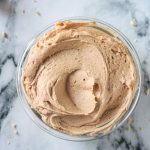 Peanut butter frosting spread in a glass bowl.
