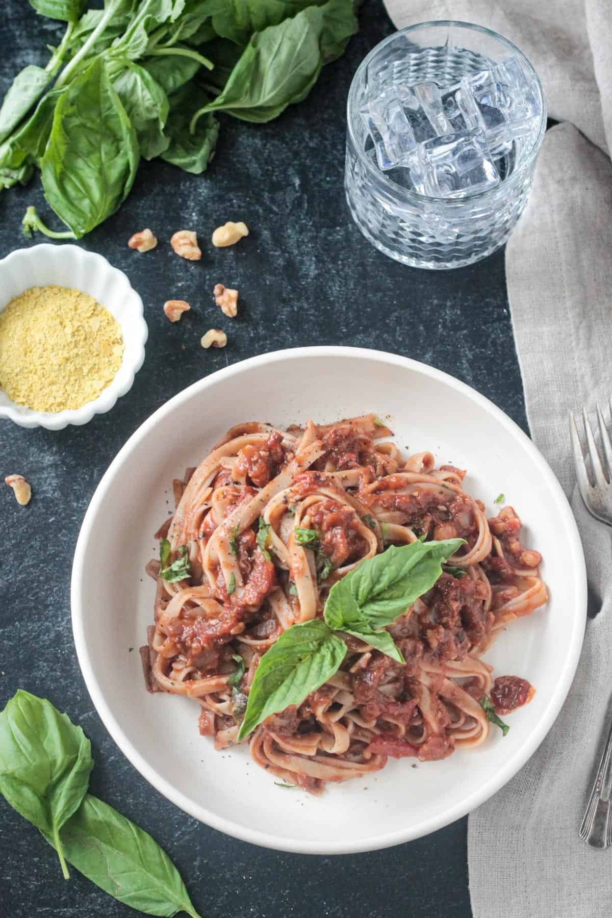 Fettuccine noodles with vegan bolognese garnished with fresh basil leaves.