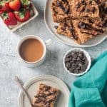 One peanut butter oatmeal bar on a plate with a fork next to a cup of coffee.