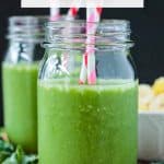 Pineapple Spinach Smoothie in a mason jar with two striped paper straws.