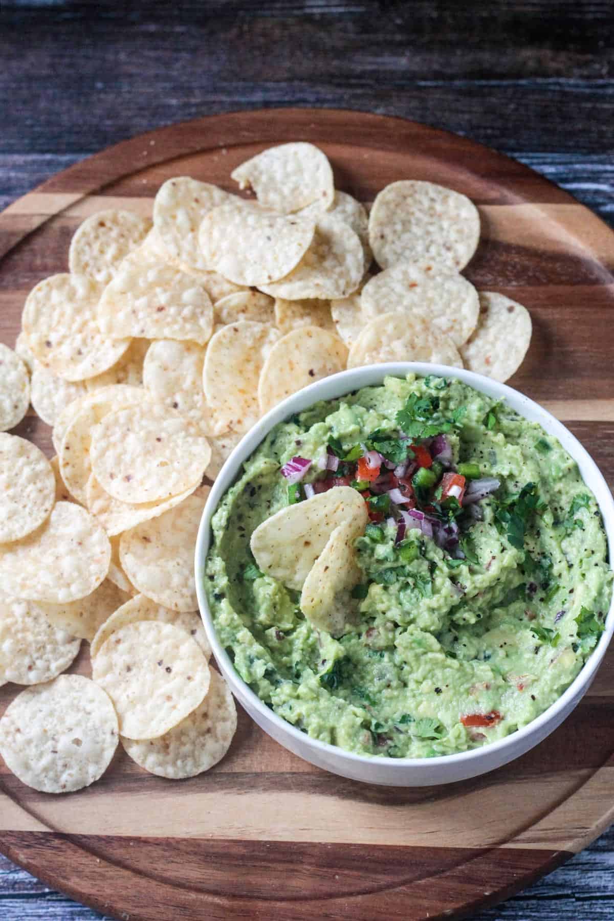 Tortilla chips being dipped into avocado dip.