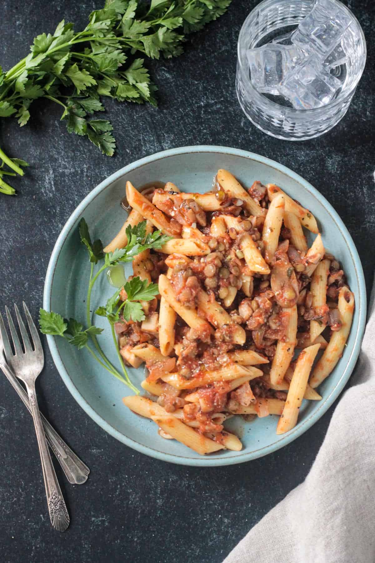 Penne with lentil mushroom lentil bolognese plated on a blue dish.