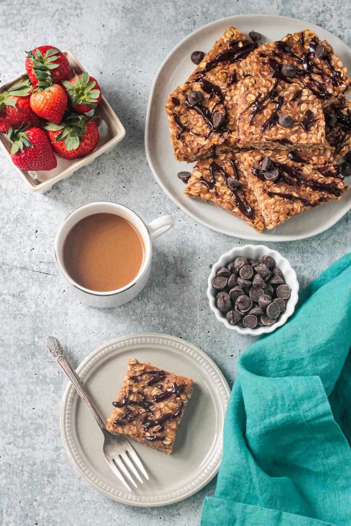 One peanut butter oatmeal bar on a plate with a fork next to a cup of coffee.