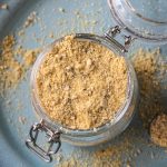 Overhead view of cheese powder in a glass jar.