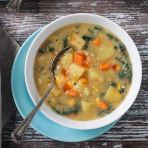 Metal spoon in a bowl of vegan potato soup.