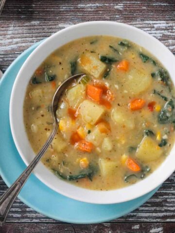 Metal spoon in a bowl of vegan potato soup.