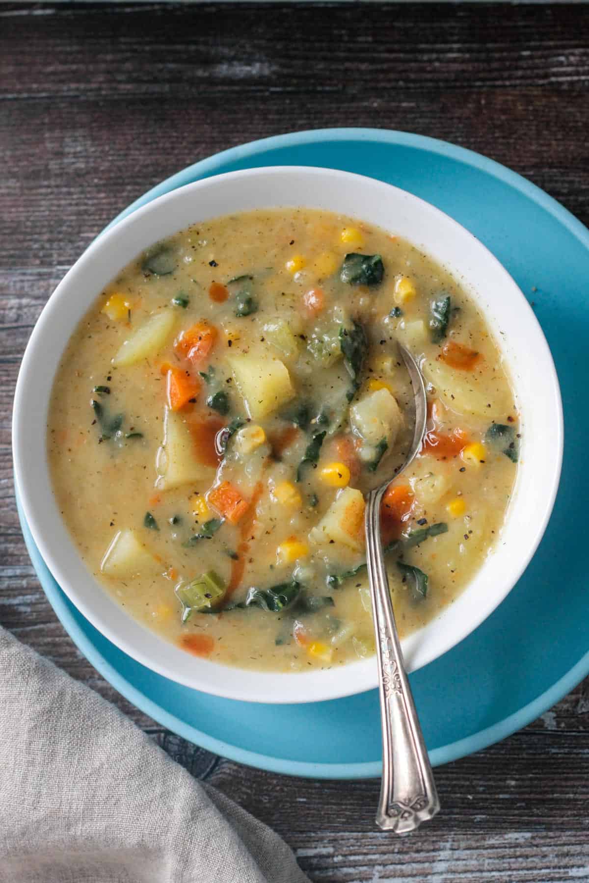 Metal spoon in a bowl of potato kale soup.