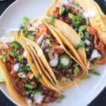 Overhead view of three tacos on a plate.