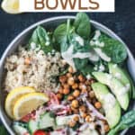 Mediterranean grain bowl with quinoa, chickpeas, cucumber tomato salad, avocado, spinach, and dressing.