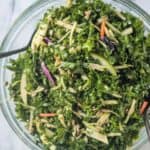 Two serving forks in a bowl full of salad.