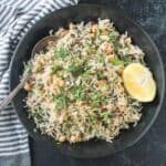 Spinach rice and chickpeas in a black serving bowl topped with a lemon wedge.