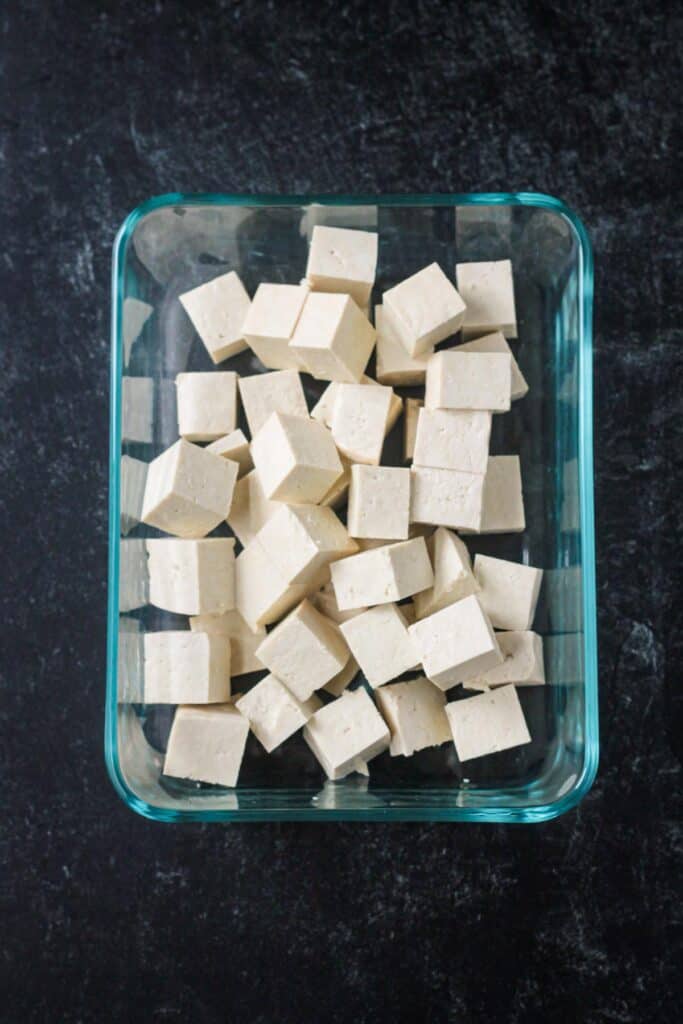 Cubes of plain tofu in glass container.
