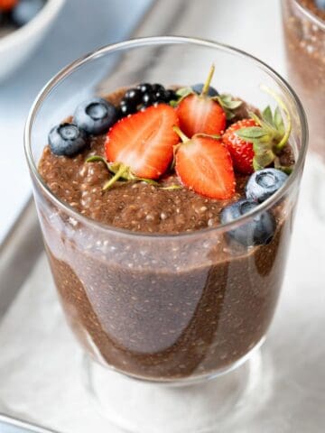 Fresh strawberries and blueberries on top of a bowl of chocolate chia pudding.