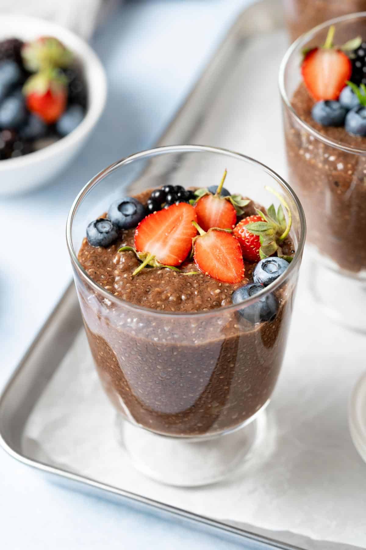 Fresh strawberries and blueberries on top of a bowl of chocolate chia pudding.