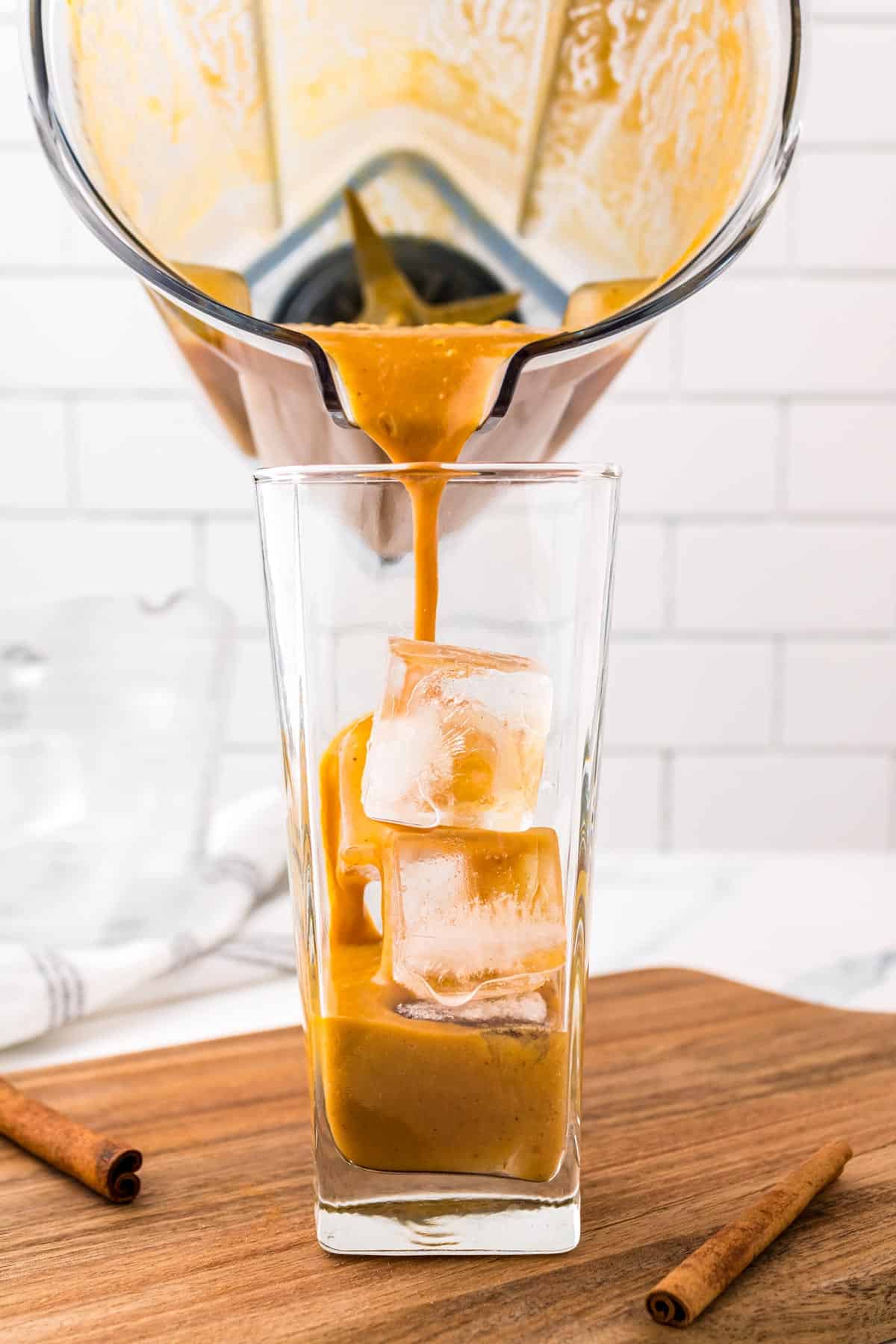Fall coffee drink being poured over ice in a glass.