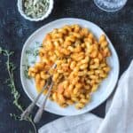 Two forks in a plate of saucy rotini noodles.