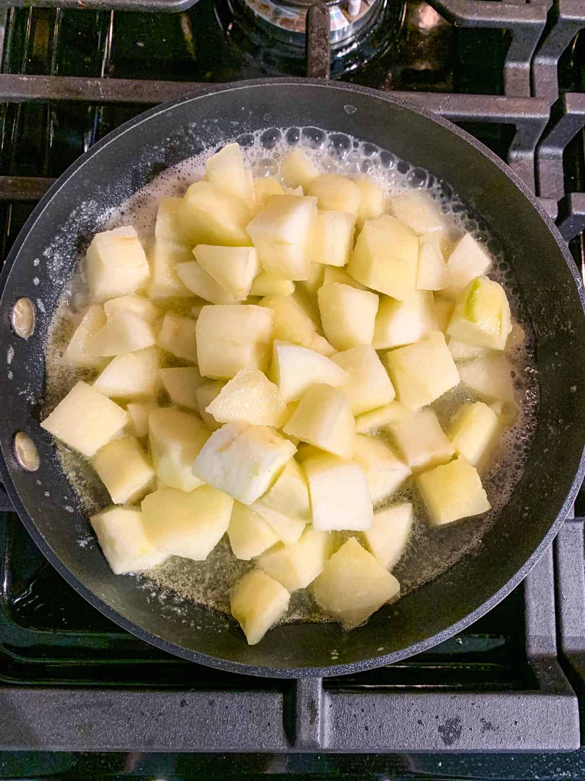 Diced apples simmering in a skillet.