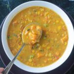 Spoonful of soup being lifted from a bowl.