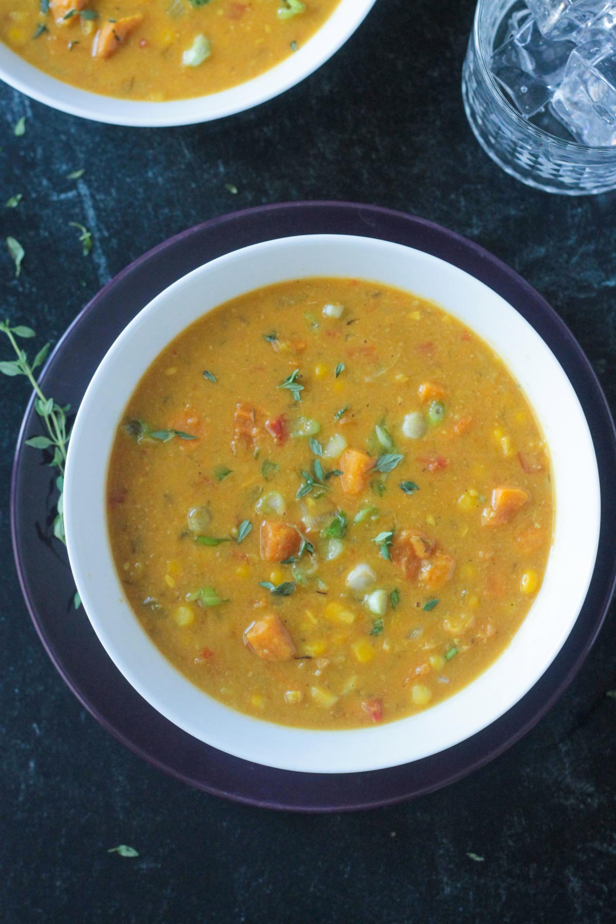 Sweet potato corn chowder in a white bowl garnished with sliced green onions.