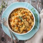 Vegan butternut squash risotto in a white bowl on a blue plate.