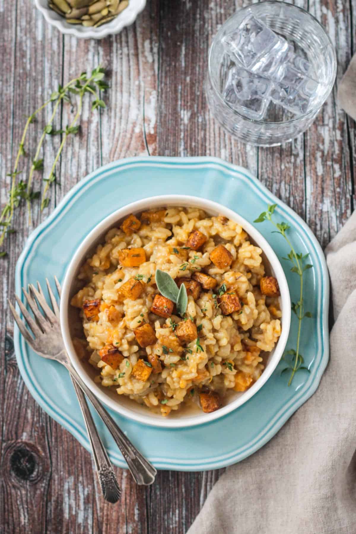 Vegan butternut squash risotto in a white bowl on a blue plate.