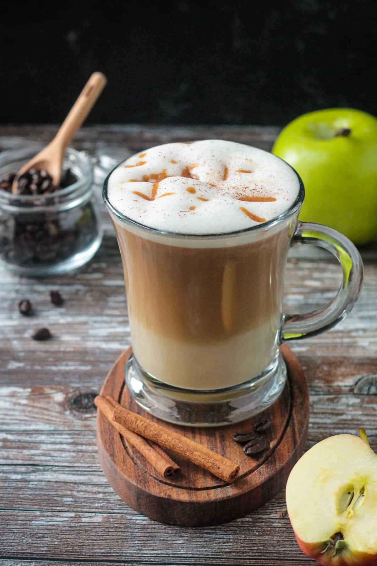 Apple coffee drink in a glass with two cinnamon sticks in front.