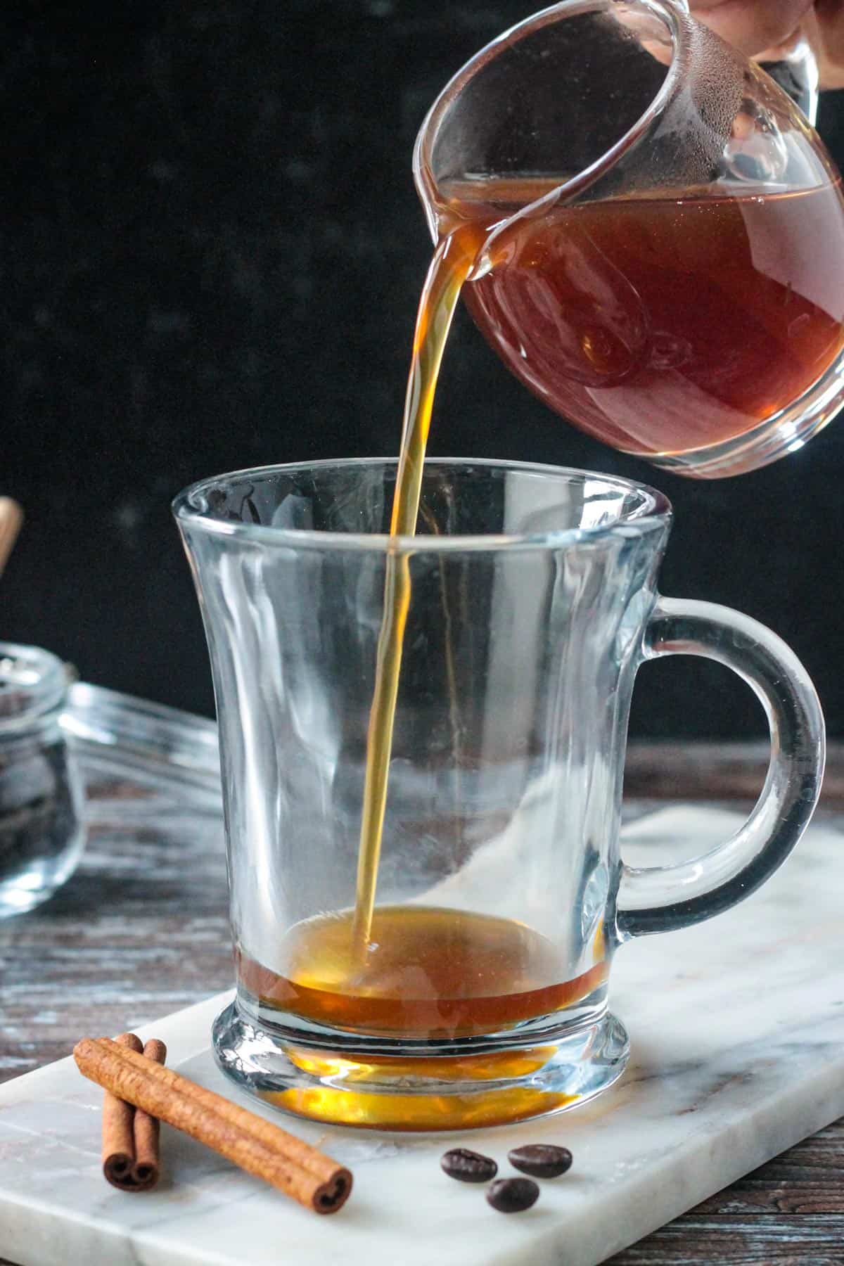 Pouring apple brown sugar syrup into a glass.