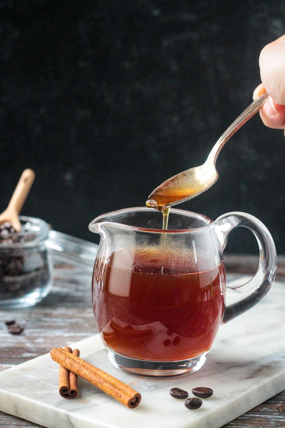 Apple brown sugar syrup drizzled off of a spoon into a glass.
