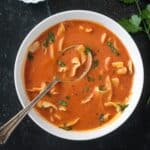 Polish tomato soup garnished with fresh cracked black pepper and chopped parsley.