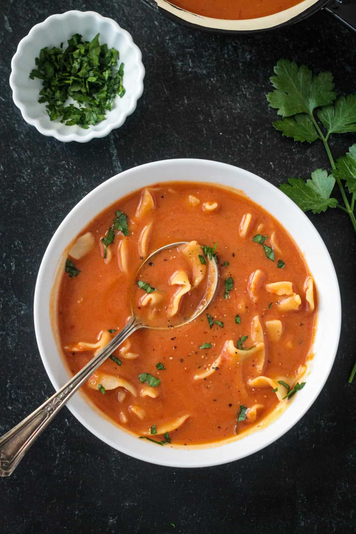 Polish tomato soup garnished with fresh cracked black pepper and chopped parsley.