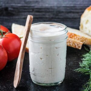 Small wooden spoon leaning against a jar of homemade vegan mayonnaise.