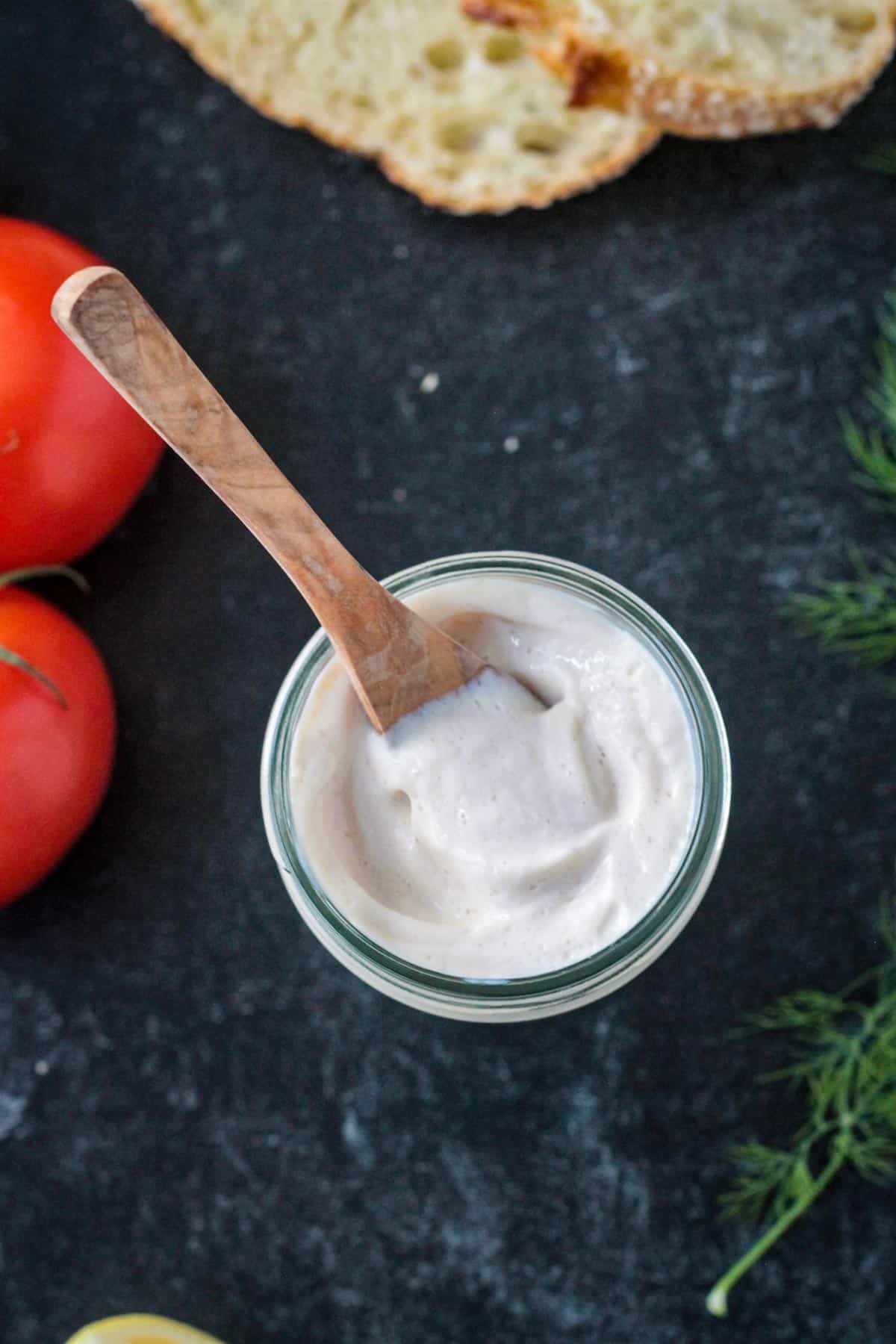 Small wooden spoon scooping some vegan mayonnaise.