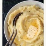 Close up of a pat of butter on top of creamy mashed potatoes.