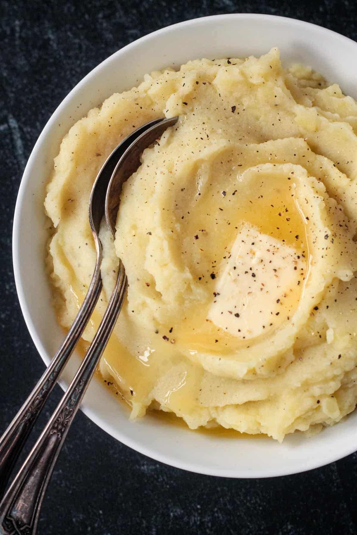 Close up of a pat of butter on top of creamy mashed potatoes.
