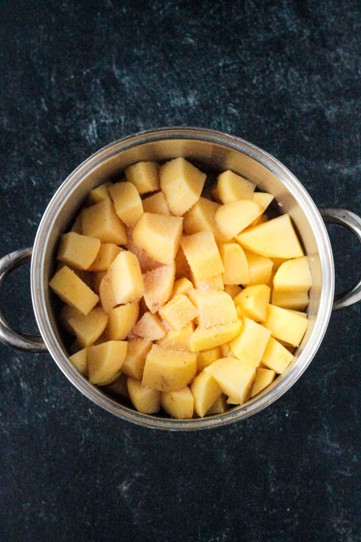 Diced potatoes in a pot with salt and pepper.